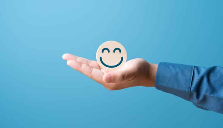 Titelbild Customer Experience Management Hand hält einen lächelnden Smiley